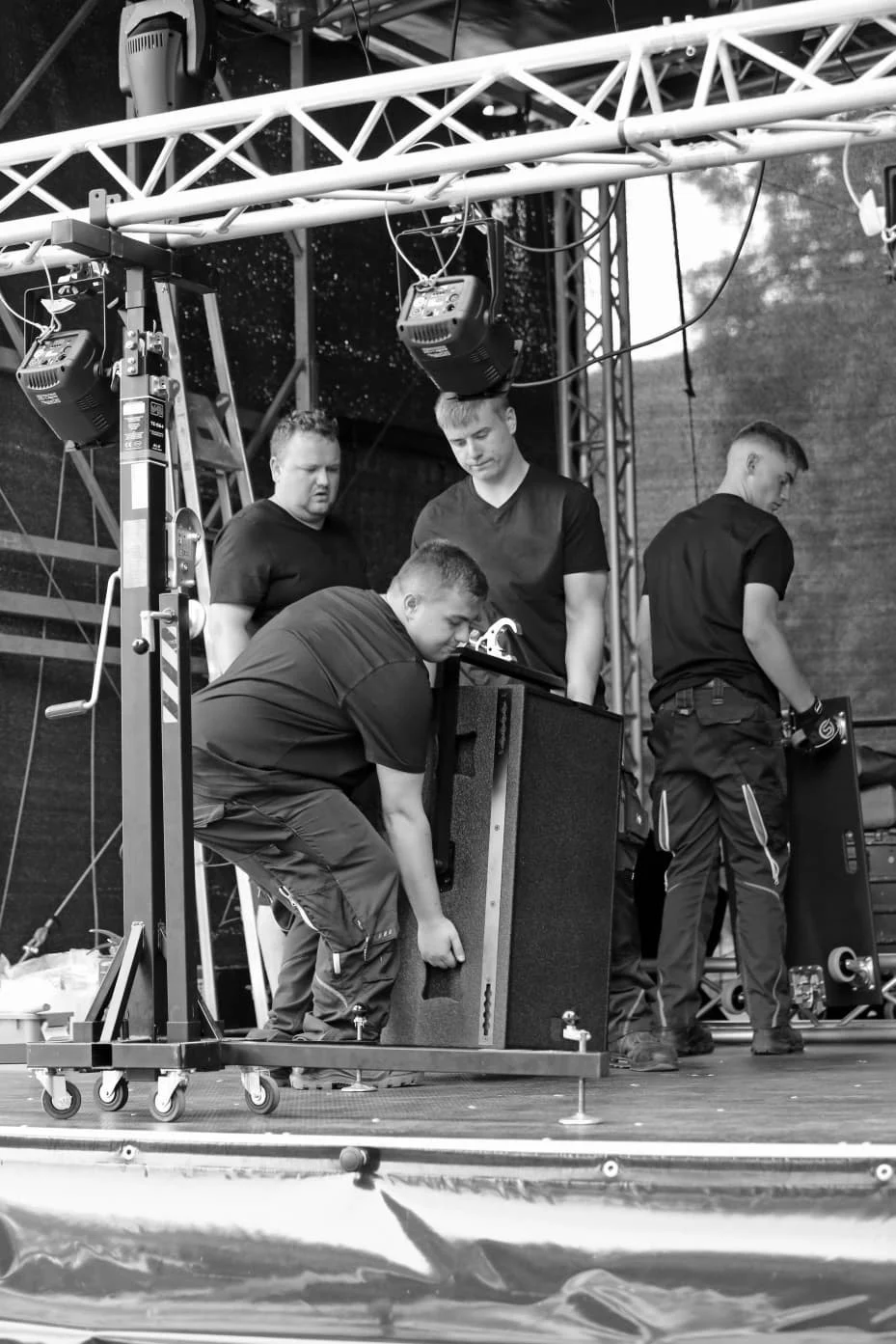 Das ZenitSound-Team hebt Lautsprecherboxen und montiert Bühnenelemente bei einer Veranstaltung.